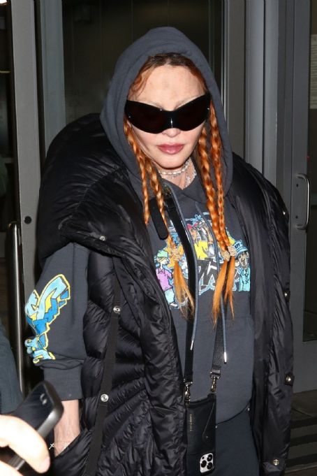 Madonna wore a grey undershirt and a graphic dark grey hoodie at JFK airport in NY