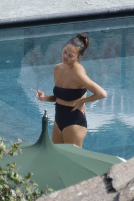 Chrissy Teigen – Seen by a swimming pool in Lake Como